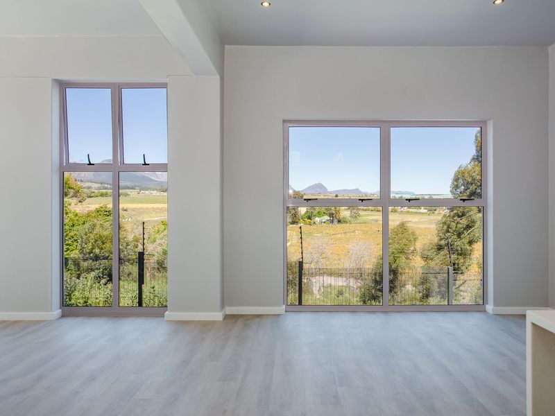 A bright, modern, and empty living area featuring large windows that offer expansive views of the surrounding landscape.