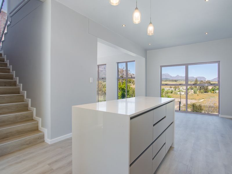 Modern open-plan living area featuring a sleek kitchen island, contemporary staircase, and large windows offering scenic mountain views.