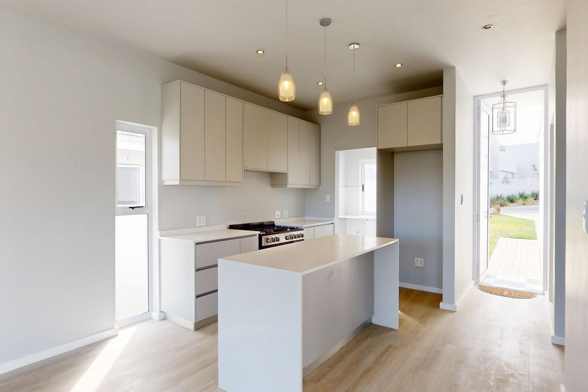 Modern, bright kitchen featuring clean-lined cabinetry, a central island, gas hob, and integrated oven, with direct access to the outdoor area.
