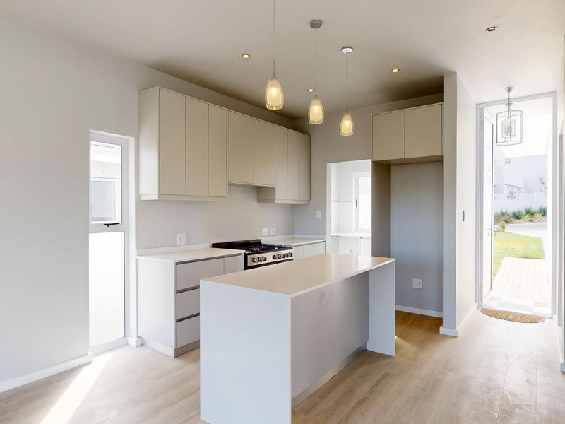Modern, bright kitchen featuring clean-lined cabinetry, a central island, gas hob, and integrated oven, with direct access to the outdoor area.