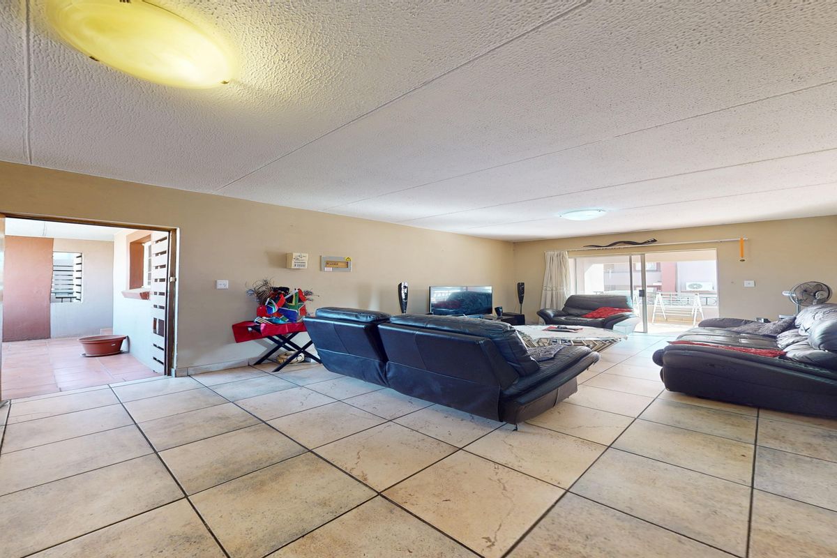 Spacious living area featuring tiled flooring, textured ceilings, and a sliding glass door leading to an outdoor balcony space.