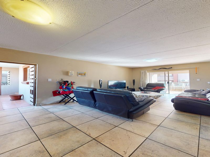 Spacious living area featuring tiled flooring, textured ceilings, and a sliding glass door leading to an outdoor balcony space.