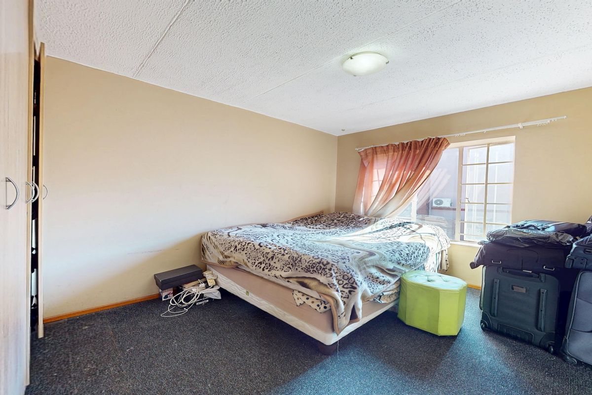 A bedroom featuring a built-in wardrobe, carpeted flooring, and a window, offering a functional space ready for cosmetic updates and modernization.