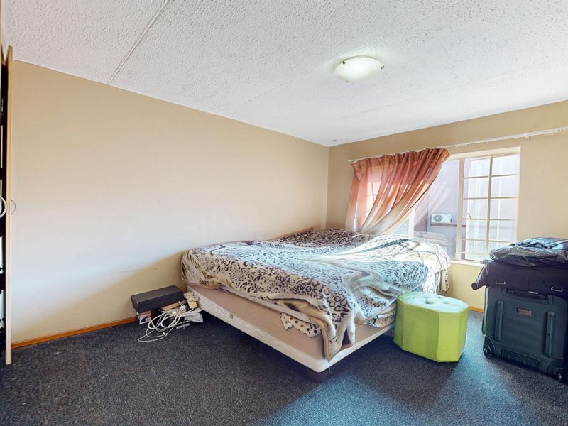 A bedroom featuring a built-in wardrobe, carpeted flooring, and a window, offering a functional space ready for cosmetic updates and modernization.