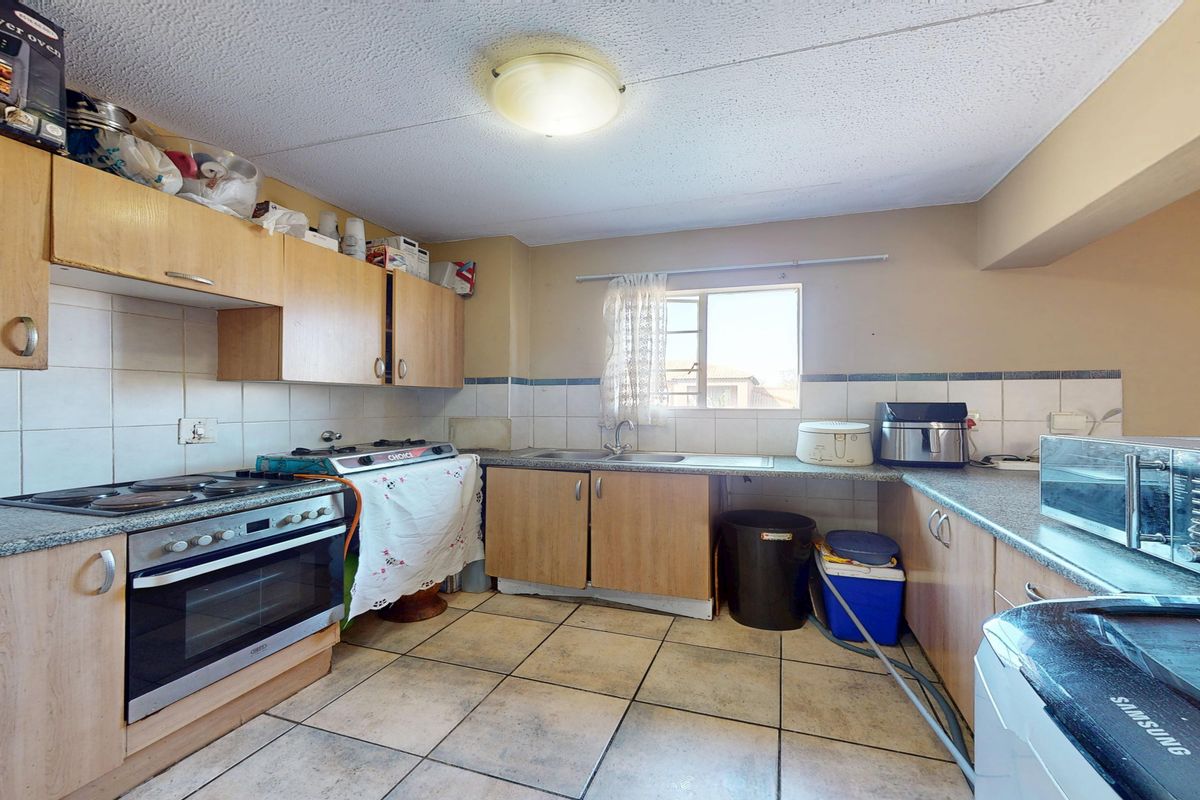A functional kitchen featuring laminate cabinetry, granite countertops, built-in oven, and hob, with tiled flooring and backsplash throughout.