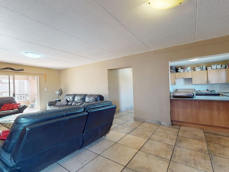 Open plan living area featuring tiled flooring, a functional kitchen with built-in cabinetry, and sliding door access to an outdoor balcony space.