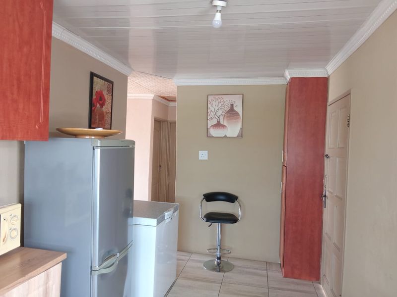 A functional kitchen area featuring built-in cabinetry, tiled flooring, and a panelled ceiling with coved detailing.