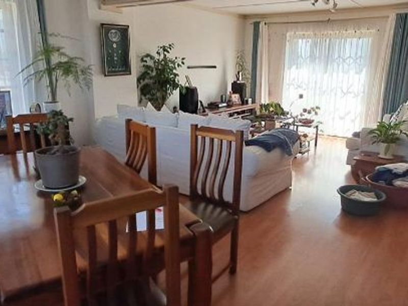 Spacious open-plan living and dining area featuring laminate flooring and large sliding glass doors that provide ample natural light.