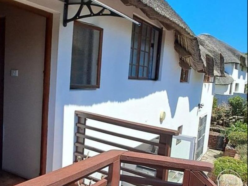 An elevated timber balcony featuring a thatched roof overhang and timber balustrade, providing outdoor access from the upper level of the property.