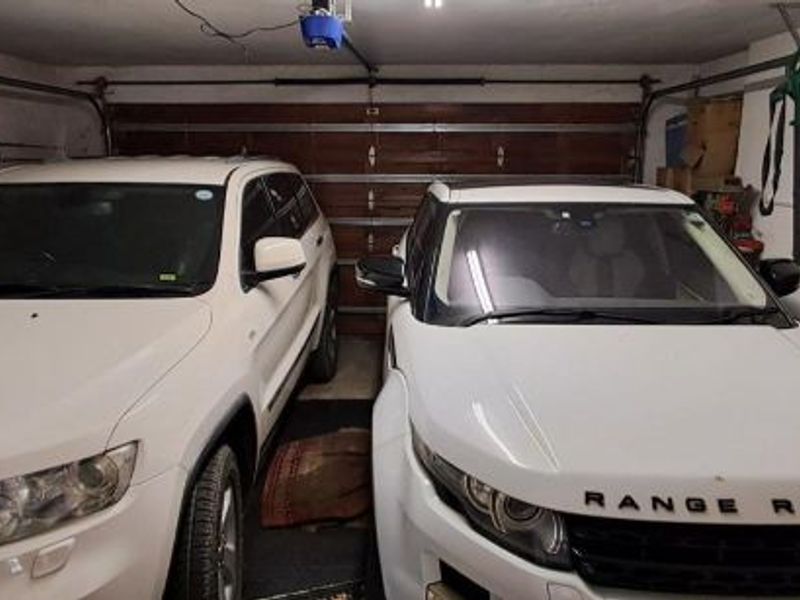 A functional double garage featuring a sectional door, automated motor, and wall-mounted storage systems for organized utility space.