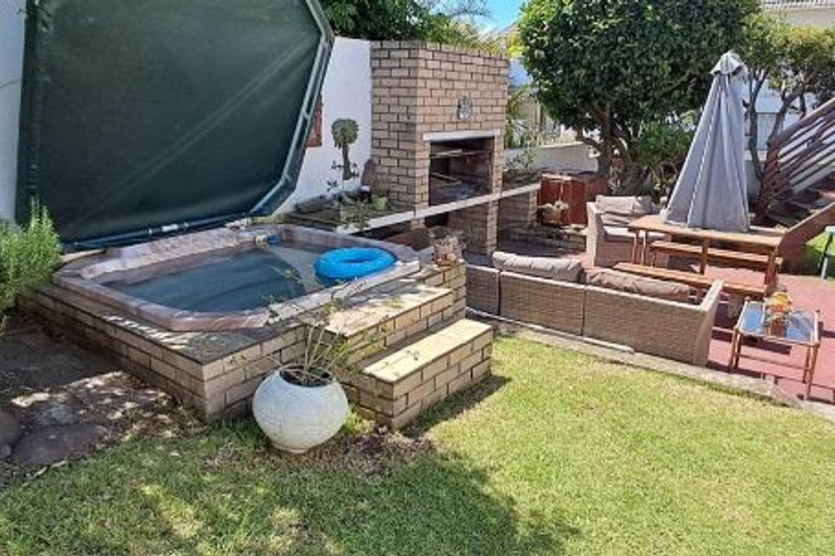 Rear garden area featuring a built-in brick braai, a sunken jacuzzi, and an external staircase leading to an upper level.