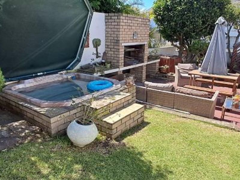 Rear garden area featuring a built-in brick braai, a sunken jacuzzi, and an external staircase leading to an upper level.