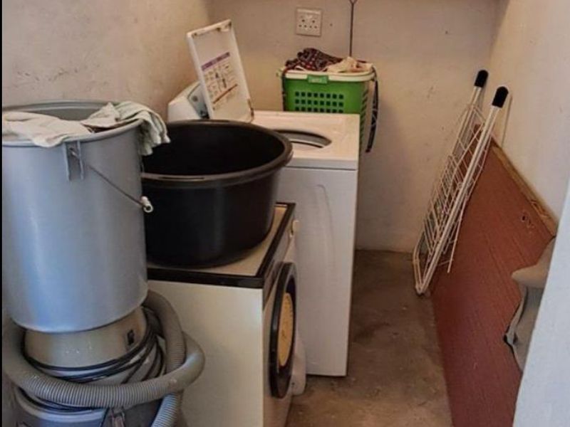 A compact utility or laundry area featuring wall-mounted shelving and concrete flooring, providing functional storage and laundry space.