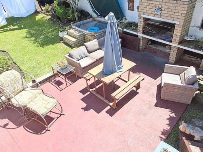 Outdoor patio area featuring a built-in brick braai, a raised spa pool, and paved flooring, ideal for outdoor entertaining.