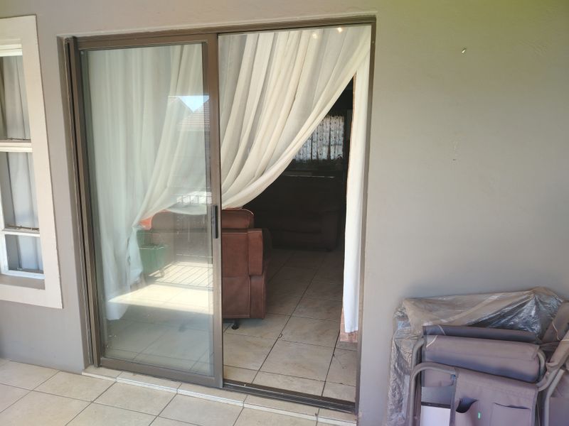 A covered patio area featuring tiled flooring and a large sliding glass door providing access to the interior living space.