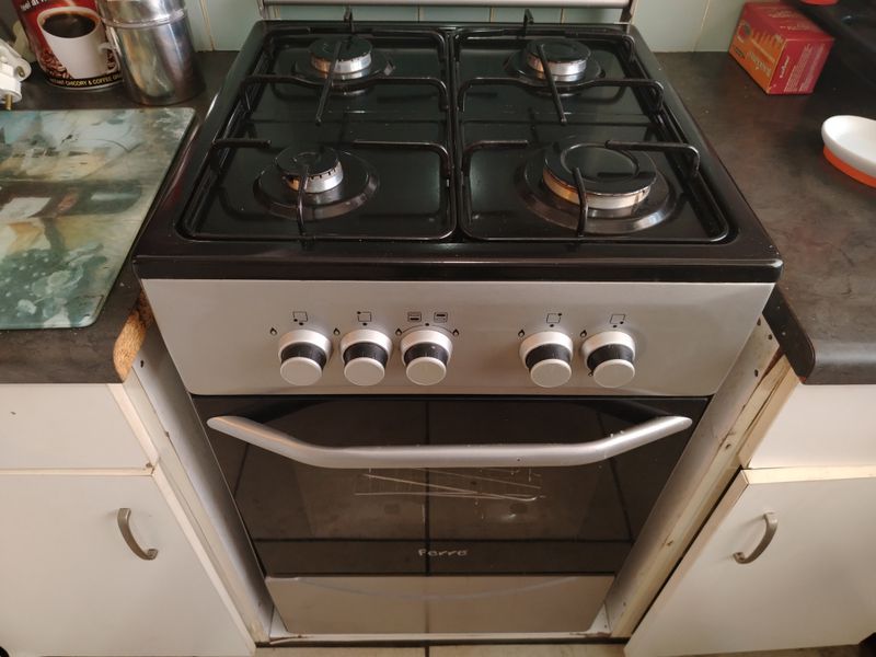 A compact kitchen area featuring a built-in gas stove and oven, set between white cabinetry and dark laminate countertops.