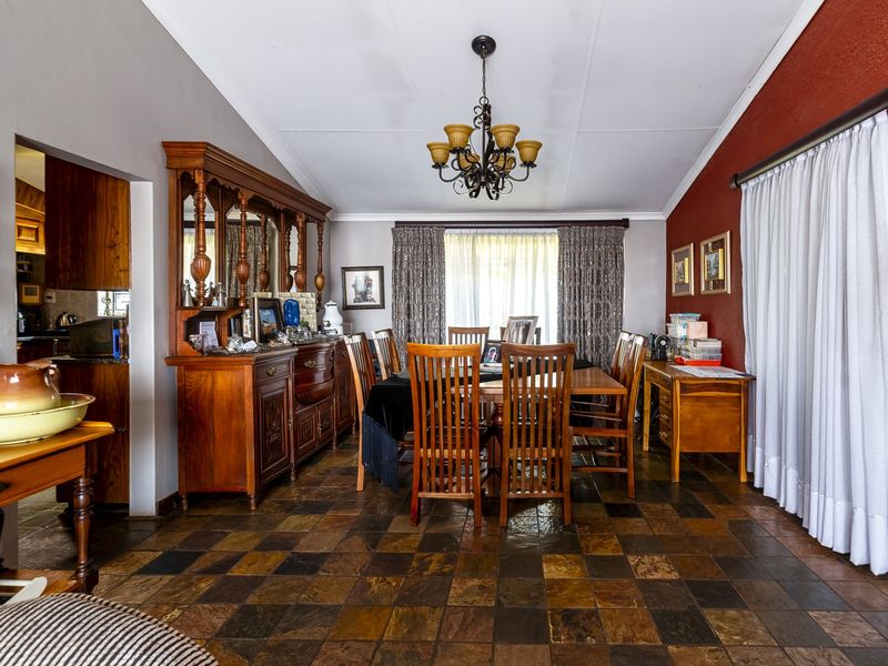 A dining room featuring traditional slate tile flooring, a central chandelier, and access to an outdoor area through a sliding glass door.