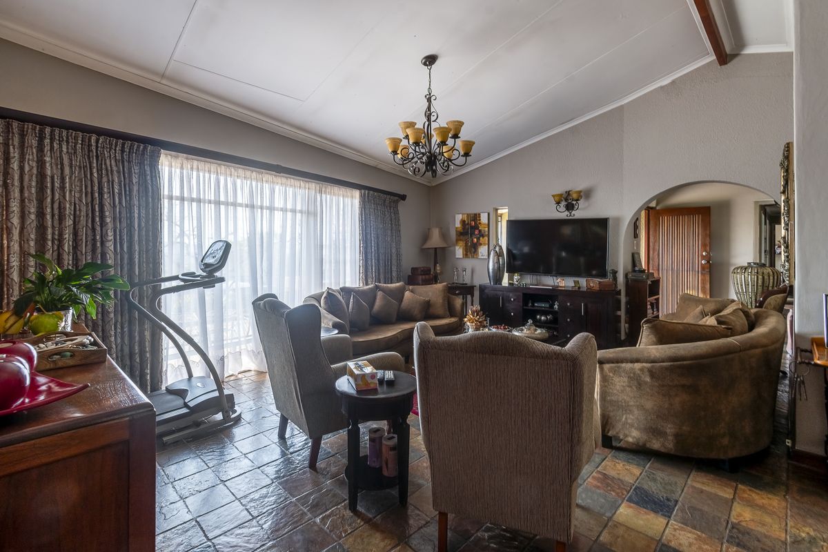 Spacious living room featuring vaulted ceilings, slate tile flooring, and an arched entryway, providing a warm and traditional atmosphere.