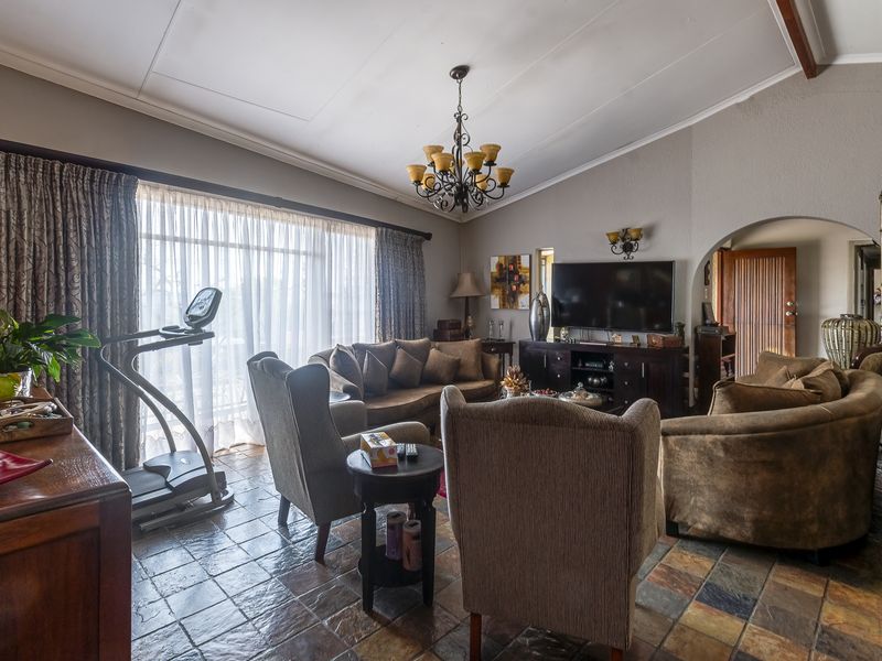 Spacious living room featuring vaulted ceilings, slate tile flooring, and an arched entryway, providing a warm and traditional atmosphere.