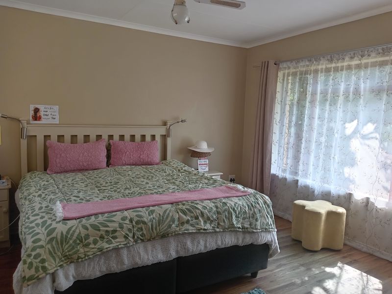 A well-lit bedroom featuring laminate flooring and a ceiling fan, offering a comfortable and functional living space.