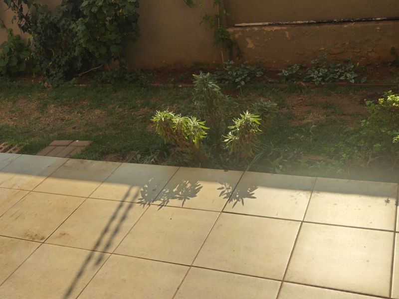 A private outdoor patio area featuring tiled flooring and an adjacent garden space with a boundary wall.