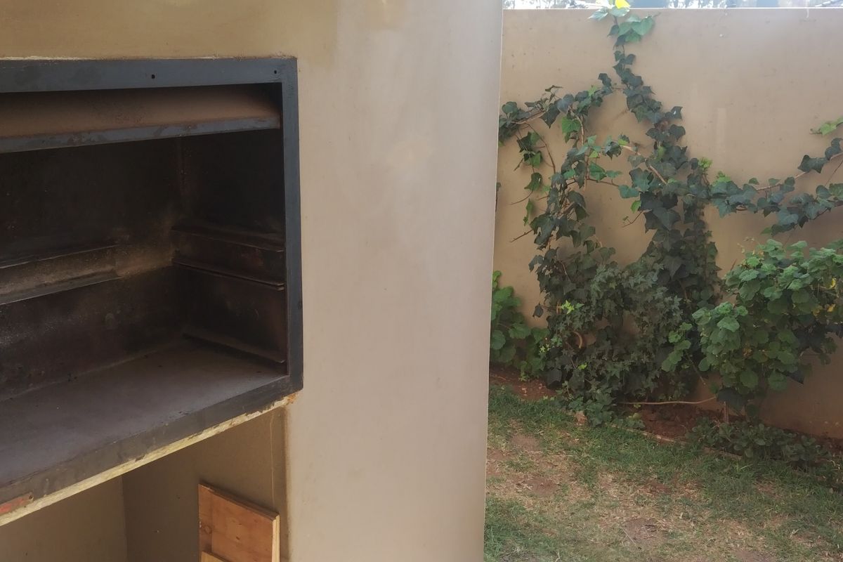 Outdoor area featuring a built-in braai unit set against a boundary wall with climbing vegetation.