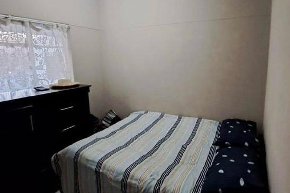 A simple bedroom featuring a window and neutral wall finishes, providing a functional space for rest.