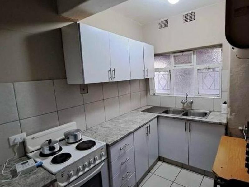 Functional kitchen featuring white cabinetry, laminate countertops, a double basin sink, and a tiled backsplash with a freestanding stove.