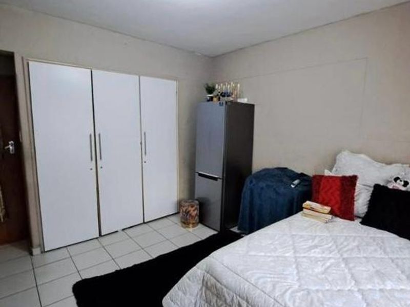 A bedroom featuring built-in cupboards and tiled flooring, requiring cosmetic updates to the wall finishes to improve the overall aesthetic.