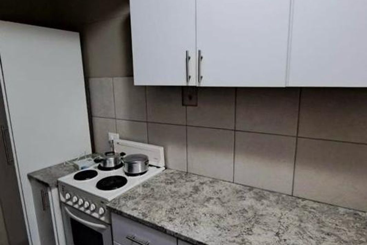 A compact kitchen featuring white cabinetry, a laminate countertop, and a built-in electric stove with oven.