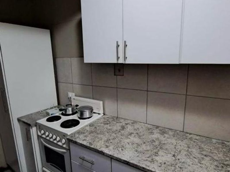 A compact kitchen featuring white cabinetry, a laminate countertop, and a built-in electric stove with oven.