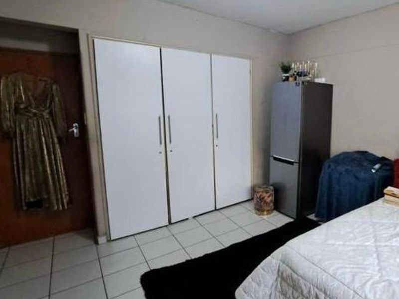A bedroom featuring built-in cupboards and tiled flooring, providing functional storage space within the room.
