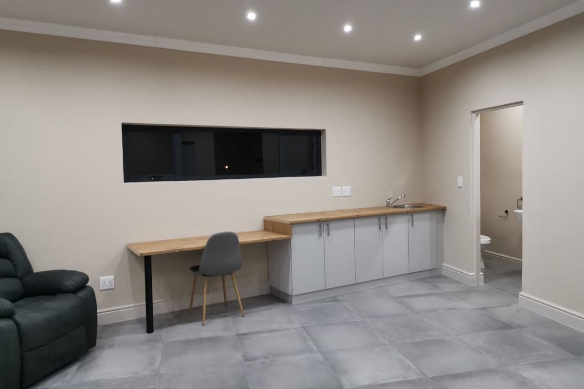 A functional utility space featuring built-in cabinetry with a wooden countertop, integrated sink, tiled flooring, and recessed downlighting, with an adjacent bathroom access.