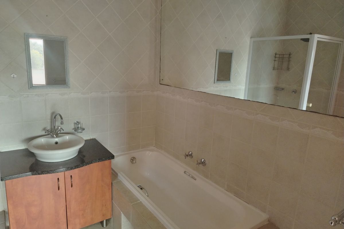 A functional bathroom featuring a vanity with a vessel sink, a built-in bathtub, and a separate shower enclosure with tiled walls.