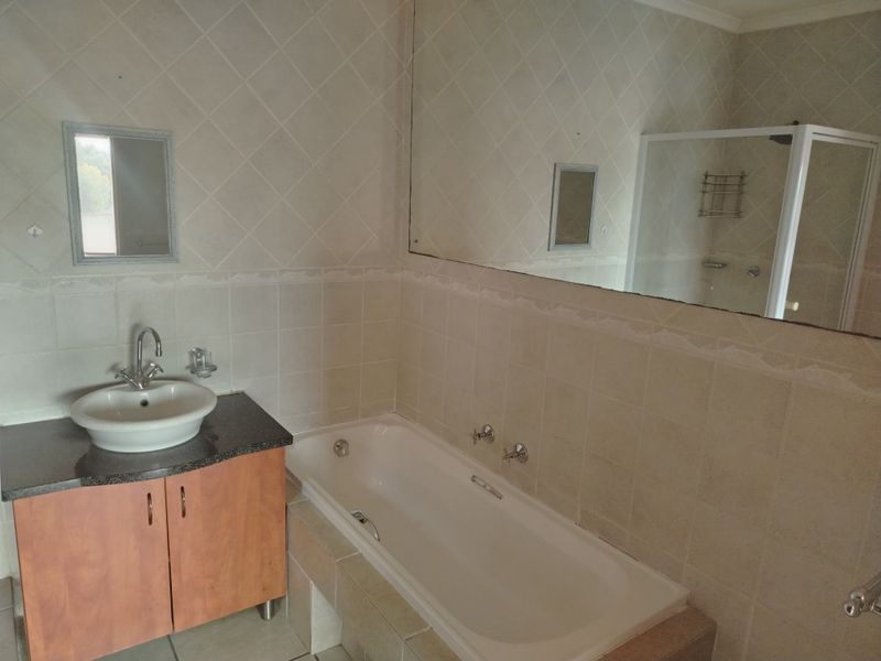 A functional bathroom featuring a vanity with a vessel sink, a built-in bathtub, and a separate shower enclosure with tiled walls.