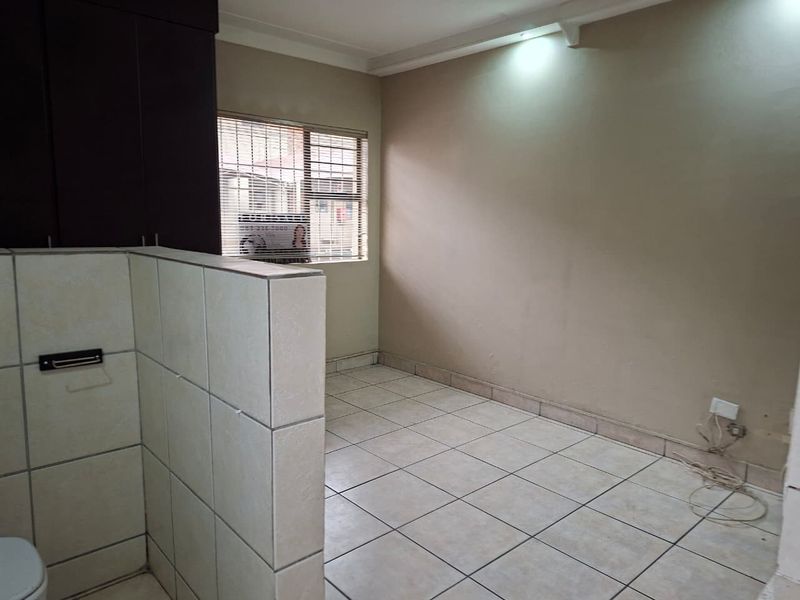An empty kitchen area featuring tiled flooring, a tiled partition wall, and built-in cabinetry, offering a blank canvas for renovation.