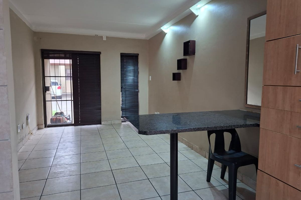 Living area featuring tiled flooring, a built-in breakfast bar, and direct access to the exterior through a security gate.