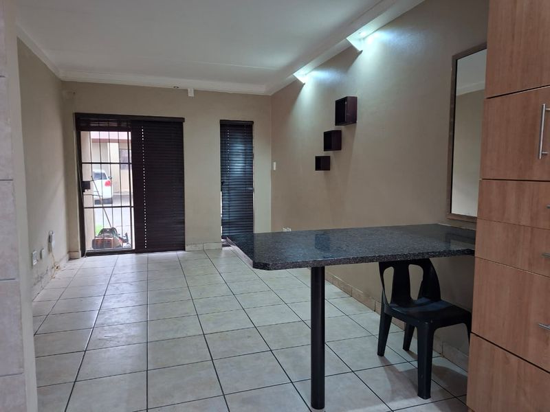 Living area featuring tiled flooring, a built-in breakfast bar, and direct access to the exterior through a security gate.