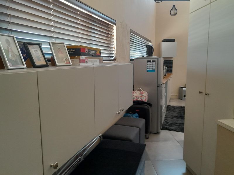 A functional kitchen area featuring built-in cabinetry, tiled flooring, and venetian blinds, offering a practical layout for daily use.