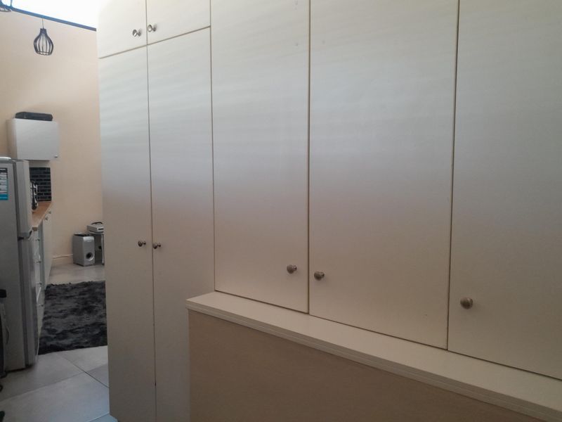 A kitchen area featuring extensive built-in white cabinetry, tiled flooring, and a functional countertop workspace.
