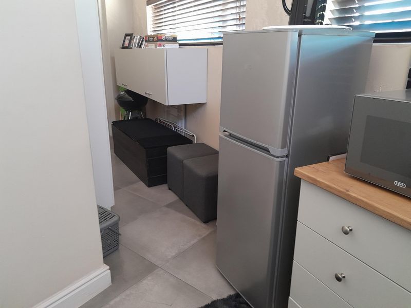 A compact kitchen area featuring tiled flooring, built-in cabinetry with a wooden countertop, and venetian blinds for natural light control.