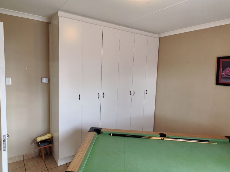 A bedroom featuring floor-to-ceiling built-in white cupboards and tiled flooring, providing ample storage space.
