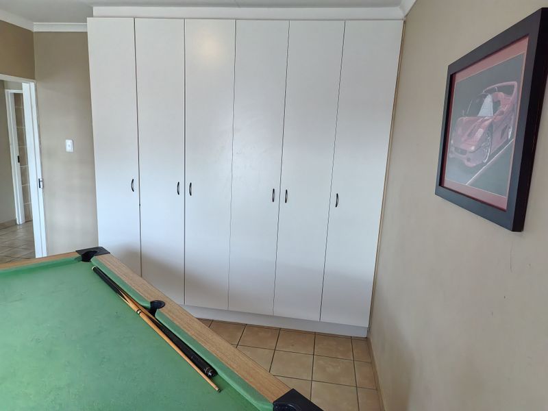 A bedroom featuring floor-to-ceiling built-in cupboards and tiled flooring, providing ample storage space.