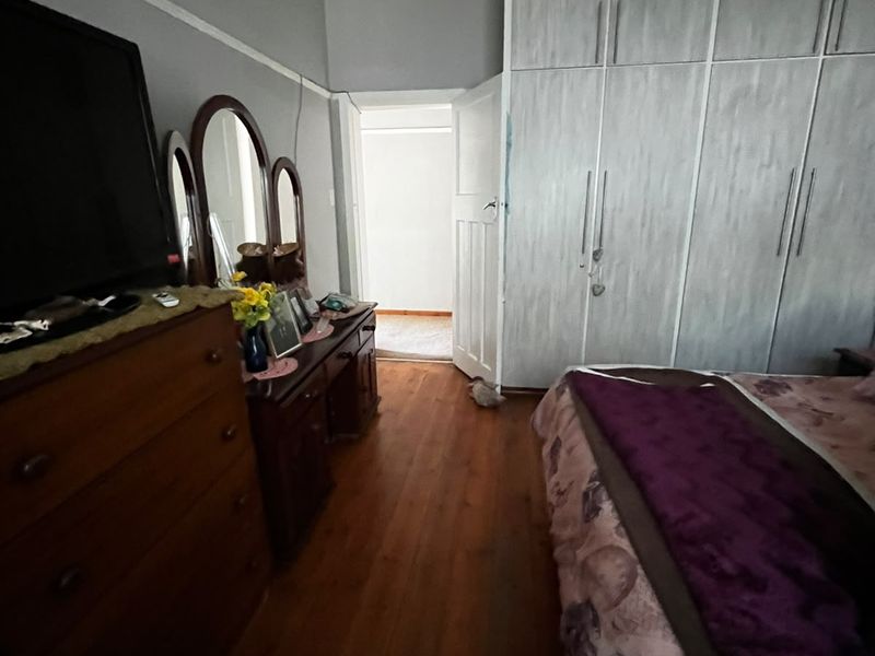 A bedroom featuring timber flooring, built-in cupboards, and classic architectural details like picture rails and coving.