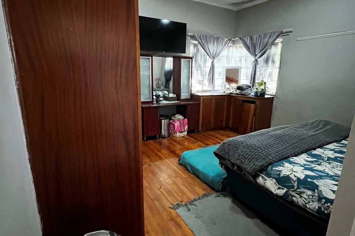 Bedroom featuring hardwood flooring and built-in cabinetry, showing signs of wear and ceiling water damage requiring maintenance.