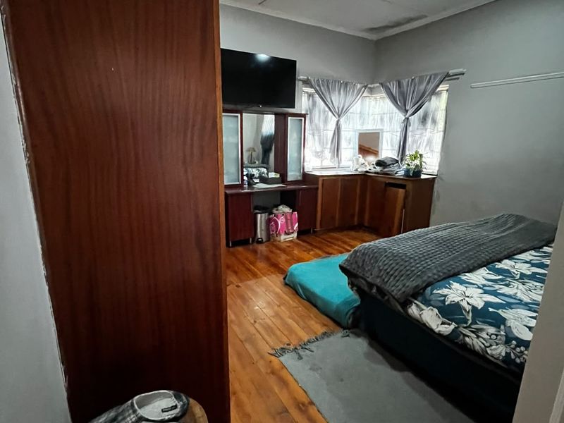 Bedroom featuring hardwood flooring and built-in cabinetry, showing signs of wear and ceiling water damage requiring maintenance.