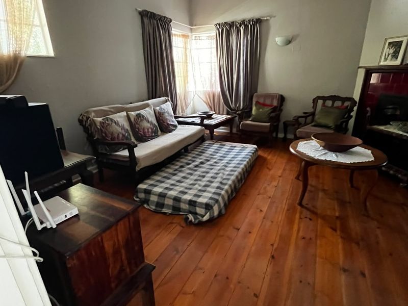 A living room featuring original hardwood flooring, a ceiling fan, and a fireplace, offering a classic foundation for renovation.
