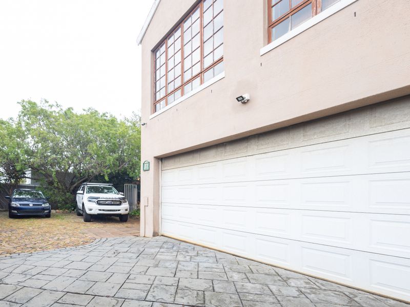 Front exterior view of the property featuring a white sectional garage door, paved driveway, and upper-level timber frame windows.