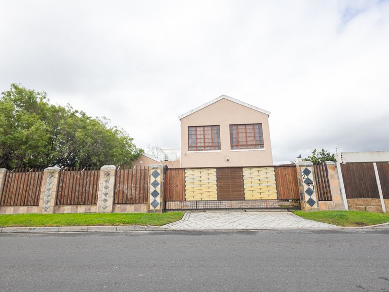 Front elevation of a two-story house featuring a secure perimeter wall, timber fencing, and a wide sliding gate with a paved driveway.