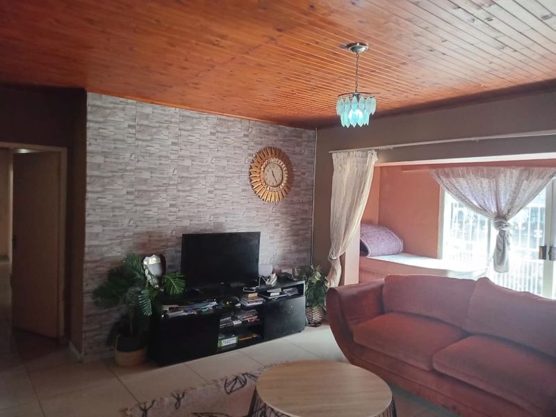Living room featuring a timber tongue and groove ceiling, tiled flooring, a textured feature wall, and a built-in window seat.
